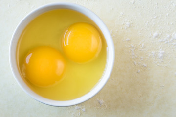 Egg yolks in a bowl on yellow background