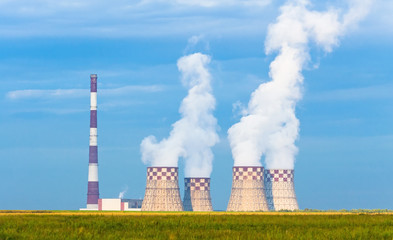 Thermal power plant рigh pipe with cooling towers on a green meadow