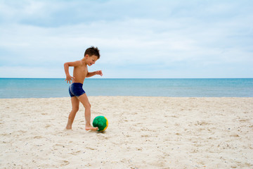 boy plays soccer on beach