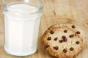snack: glass of milk and chocolate chip cookies on wooden background