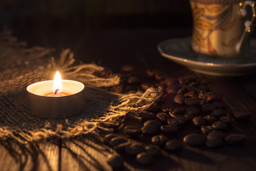 The candle burns near the bean and coffee Cup