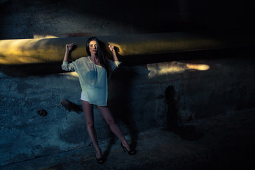Beautiful alone girl and abandoned sewerage underground with ray of sunshine.