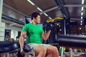 Muscular man lifts a dumbbell in the gym.