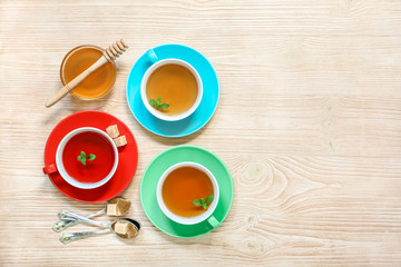 Tea Collection of three different types of tea - mint, hibiscus and herbal tea in cups isolated on wood background.