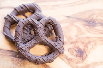 Chocolate dipped and covered pretzels over a wooden background.