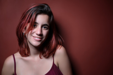 Fototapeta premium Beautiful red haired teenage girl photographed on a matching red background