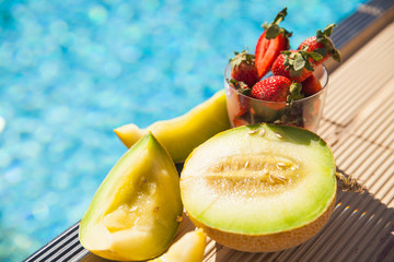 melon and strawberries near the swimming pool in summer