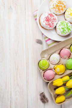 Easter with yellow tulips, colorful eggs and traditional cakes