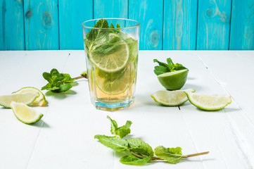 Mojito cocktail with lime and mint in highball glass on a wood table. Blue background
