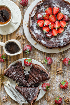 Chocolate pancakes with sauce and strawberries for breakfast