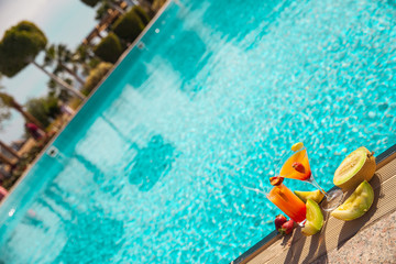 Cold cocktail near the pool in summer time with strawberry and orange
