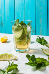 Mojito cocktail with lime and mint in highball glass on a wood table. Blue background
