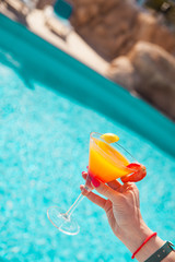 Cold cocktail near the pool in summer time with strawberry and orange
