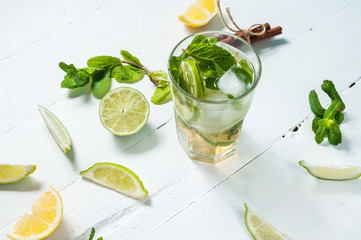 Mojito cocktail with lime and mint in highball glass on a wood white background