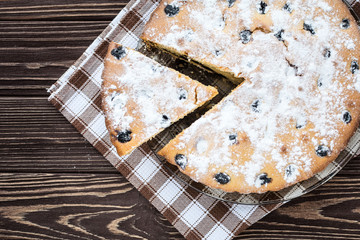 Сherry pie sprinkled powdered sugar on wooden background
