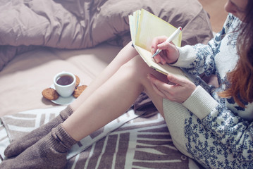 Girl writing in a notebook sitting on the bed