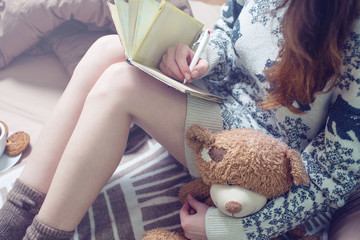 Girl writing in a notebook sitting on the bed