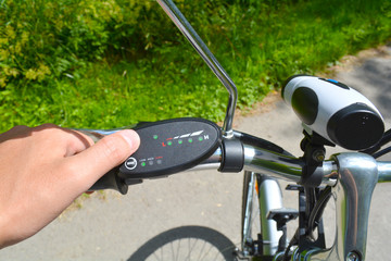 Fototapeta na wymiar Turning on electric bike, E-bike or bicycle. Pressing a button on control board or controller to choose speed and power level. Unfiltered, with natural lighting