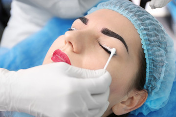 Naklejka premium Young beautiful woman making permanent makeup in cosmetology salon