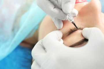 Young beautiful woman making permanent makeup in cosmetology salon