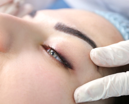 Young beautiful woman making permanent makeup in cosmetology salon