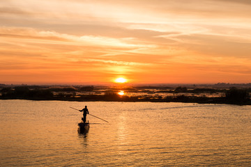Fototapeta premium fisherman on long tail boat in the lake with sunrise background
