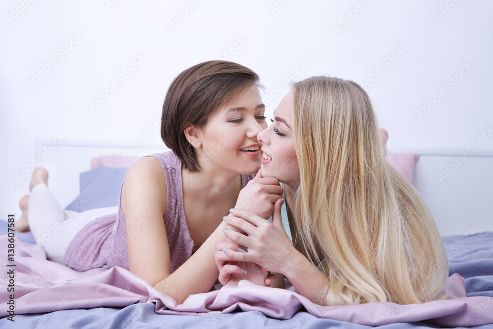 Wall mural Young lesbian couple lying on bed at home