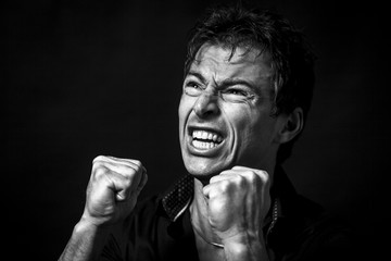 Close up portrait of isolated angry man. Monochrome picture, black background