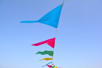 Triangle flags hanging on the rope against the blue sky. Unfiltered, with natural lighting. Multi colored triangular flags on celebration party.