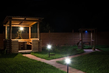 arbor and barbecue in backyard at night