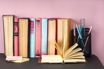 Open book, stack of colorful hardback books on light table. Back to school. Copy space for text