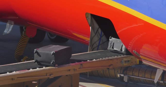 Baggage handlers load luggage and cargo under a jet before departure.	 	