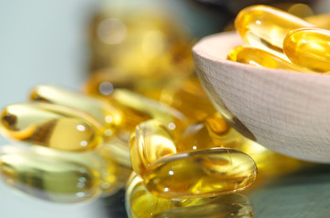 Wooden spoon of pills and oil fish capsules. Omega 3 pills fish oil capsules. Closeup fish oil dietary supplement.