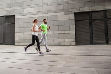 Side view of couple running in an urban environment.