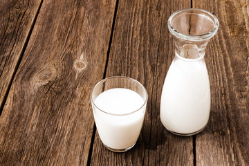 Glass and bottle of milk on old wooden table