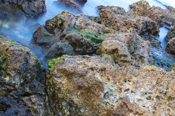 Sea wave on a background of stones in a long exposure.