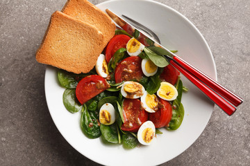 green spring salad with spinach, tomatoes and eggs. on stone background