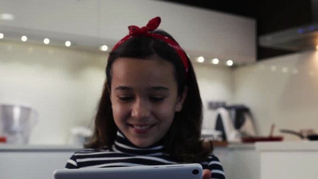 Ni&ntilde;a jugando con tablet mientras su madre cocina