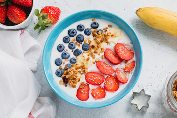 Yogurt bowl with fresh strawberries, blueberries and granola. Table top view