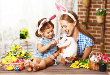 Happy easter! family mother and child daughter playing with a rabbit at home for the holiday