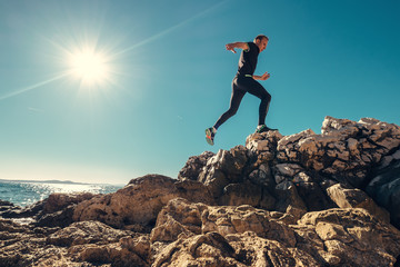 Man runs on rocky sea side