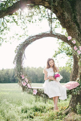 Beautiful woman in white dress on swing outdoors with flowers