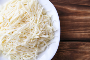 White bowl of sliced cabbage on wood background