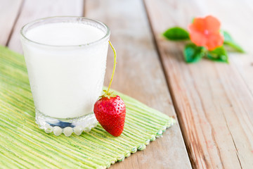 Healthy breakfast at spring sunny day. Goat yogurt, fresh strawberry and flower on a wooden background. Eating healthy and diet concept. 