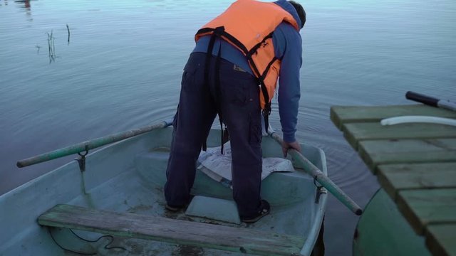 Unrecognizable man in lifejacket in a boat at the evening