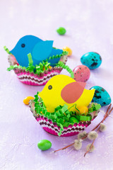 Easter decorations children's table. Easter table decoration nest with baby bird paper and candy, painted quail eggs. Copy space.