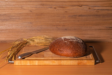 Loaves of fresh bread with ears of corn on the table © leomalsam