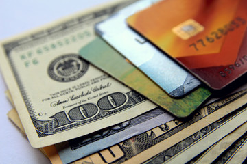 Stack of credit cards and dollars, close-up view.