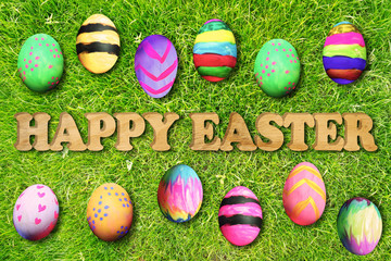 Happy Easter word and eggs on grass