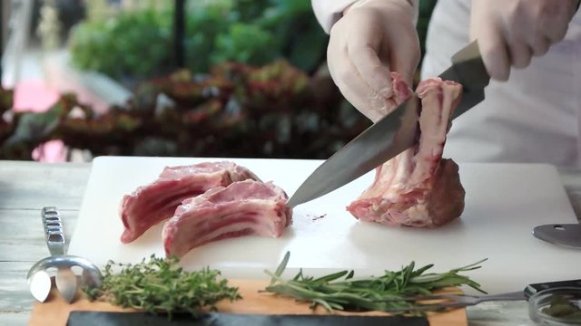 Hands cutting meat in slow-mo. Herbs and cooking board. Make a special dish.